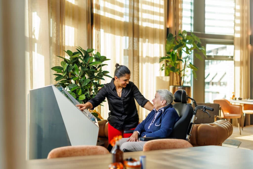 Medewerker en bewoner die een liedje uitkiezen bij de jukebox