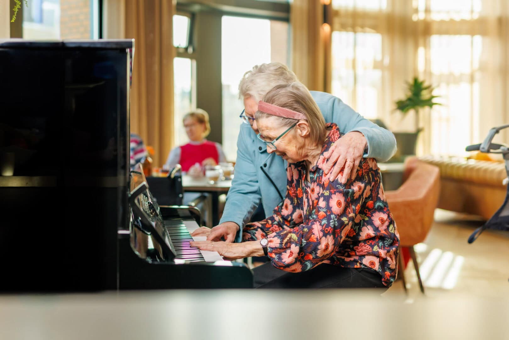 Bewoner met vrijwilliger achter piano